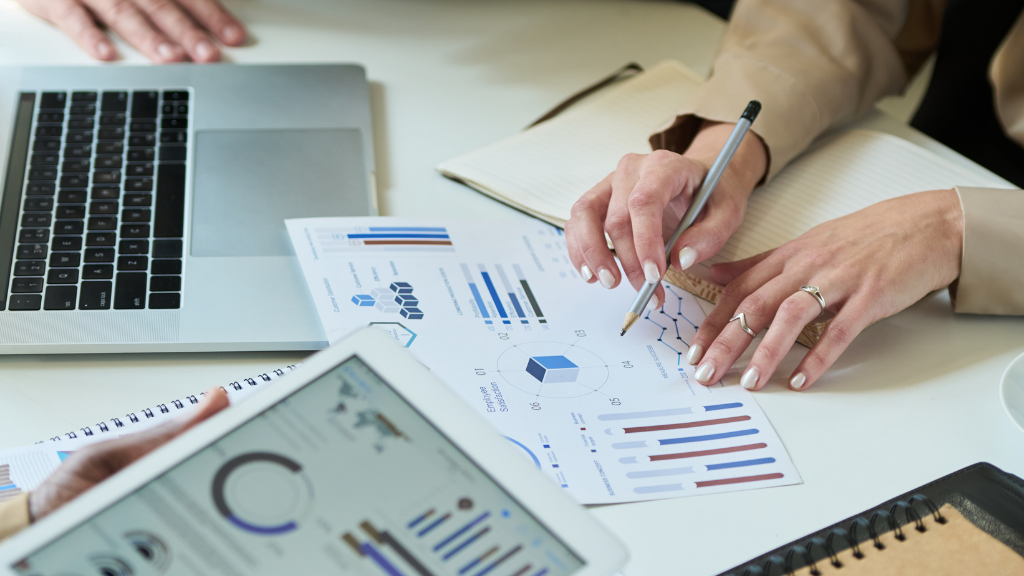 Person in a blue suit writing on a clipboard with a pen indoors.