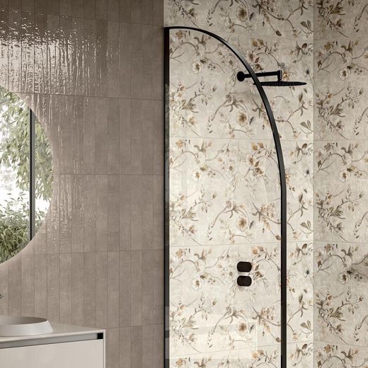 La moderna zona doccia è caratterizzata da una porta in vetro ad arco con cornice nera, in contrasto con le piastrelle color tortora, sia chiare che a tinta unita, decorate con motivi floreali.