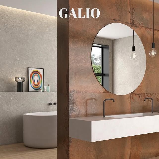 Un bagno moderno con specchio rotondo, lavabo sospeso e una parete decorativa con effetto ruggine.