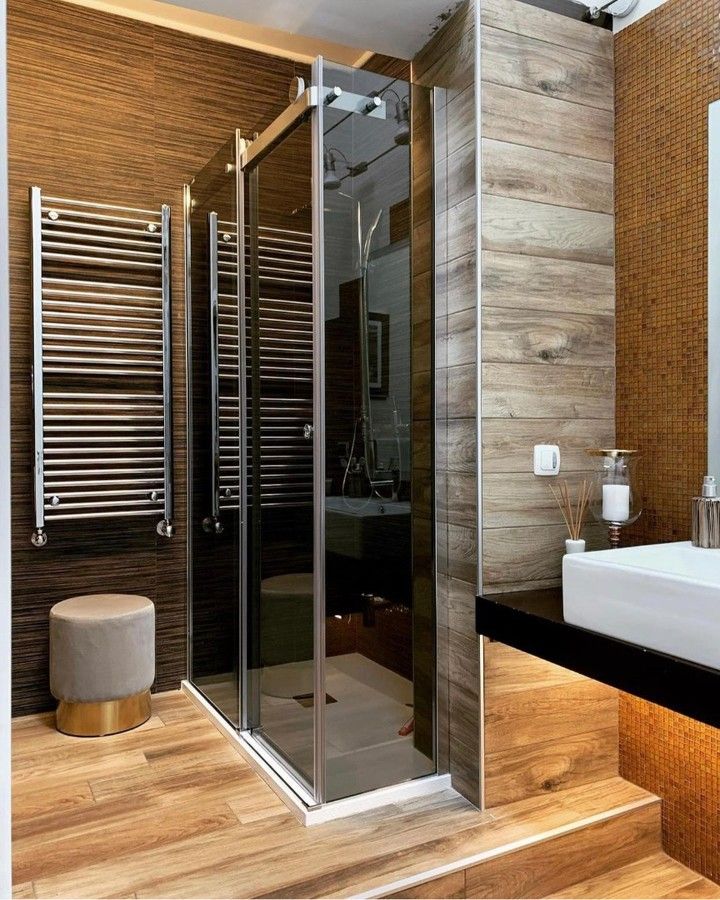 Bagno moderno con box doccia in vetro, scaldasalviette, sgabello di colore chiaro e mobile lavabo con finiture in legno.