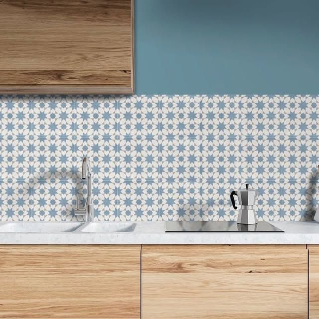 Un bancone da cucina con mobili in legno chiaro, un lavello e un rivestimento a piastrelle con motivo a stelle blu e bianche.