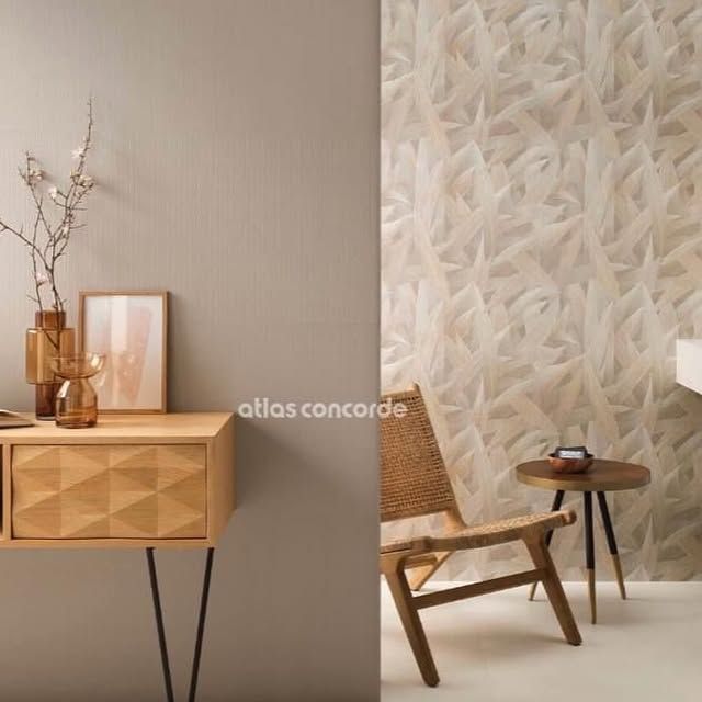 Una stanza che mostra un mobile in legno chiaro sulla sinistra e una parete con una trama a foglie, con una sedia e un tavolino sulla destra.