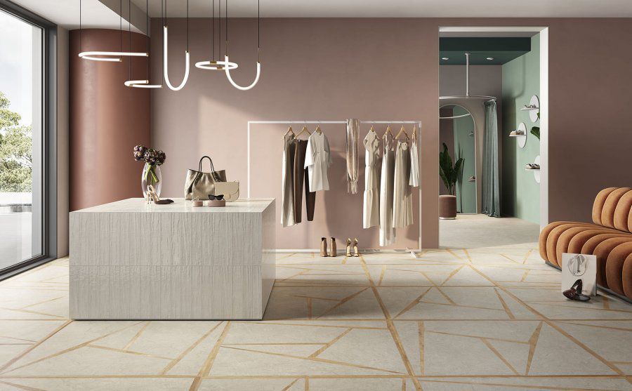 L'allestimento di un negozio di abbigliamento, caratterizzato da un'isola in marmo, uno stand per gli abiti, pareti dai toni tenui e piastrelle del pavimento con motivi geometrici.