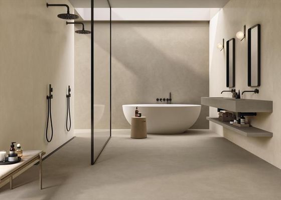 Un bagno moderno con doppia doccia, vasca da bagno bianca e doppio lavabo minimalista in cemento dai toni neutri.