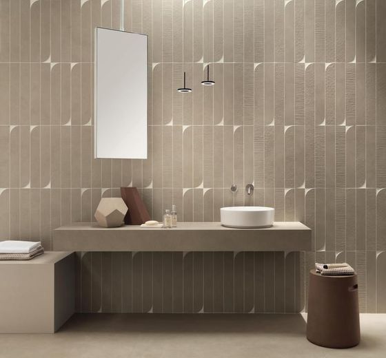Un bagno moderno caratterizzato da un mobile lavabo sospeso in pietra beige, un lavabo a ciotola bianco e pareti con texture a motivi geometrici.