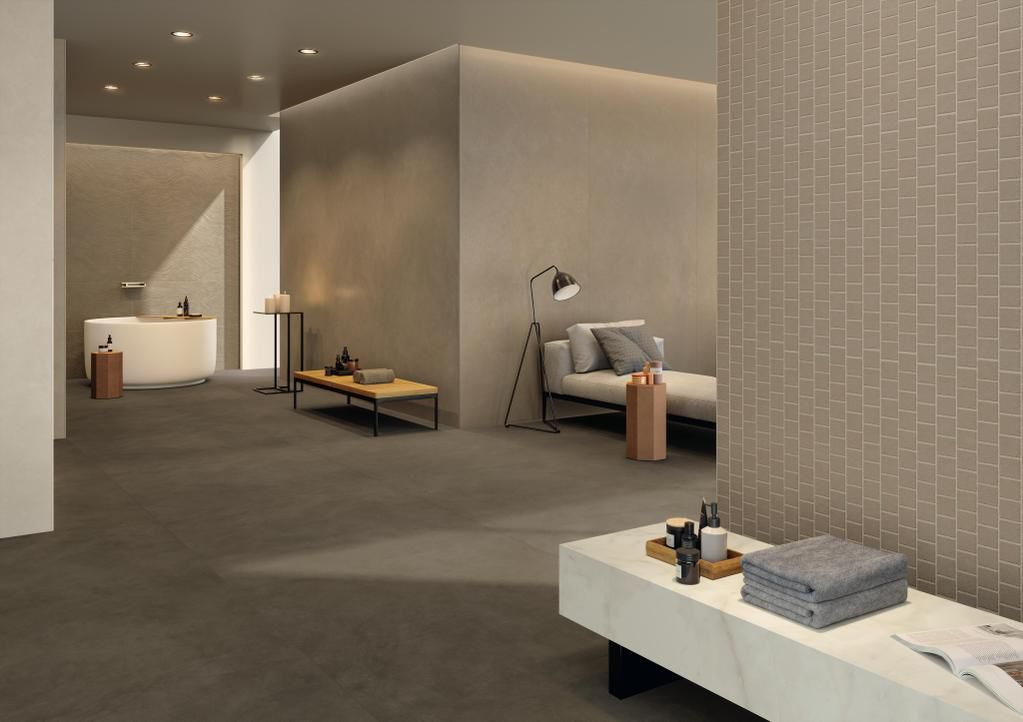 Un'area benessere moderna e minimalista dai toni neutri, dotata di lettino, vasca da bagno e sedute con finitura effetto pietra.