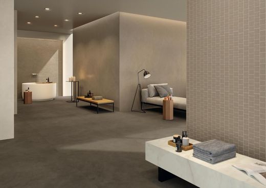 Un'area benessere moderna e minimalista dai toni neutri, dotata di lettino, vasca da bagno e sedute con finitura effetto pietra.