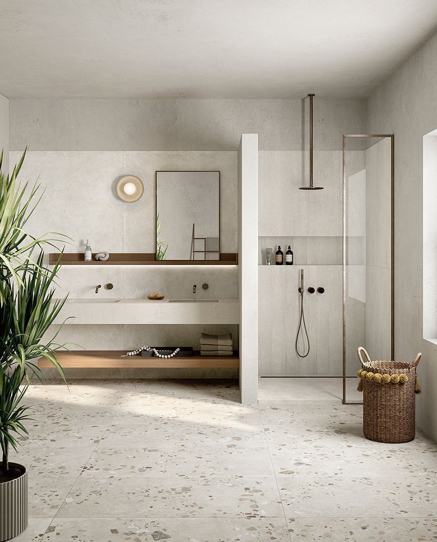 Un bagno minimalista con pavimento in terrazzo, mobile lavabo sospeso in legno, specchio a parete e box doccia in vetro.