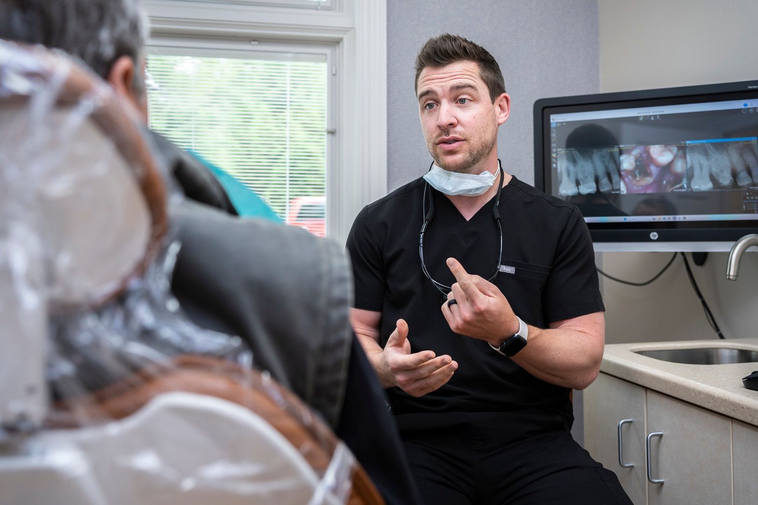 Dr. Crawford is talking to a patient in a dental chair at Maley Family Dental