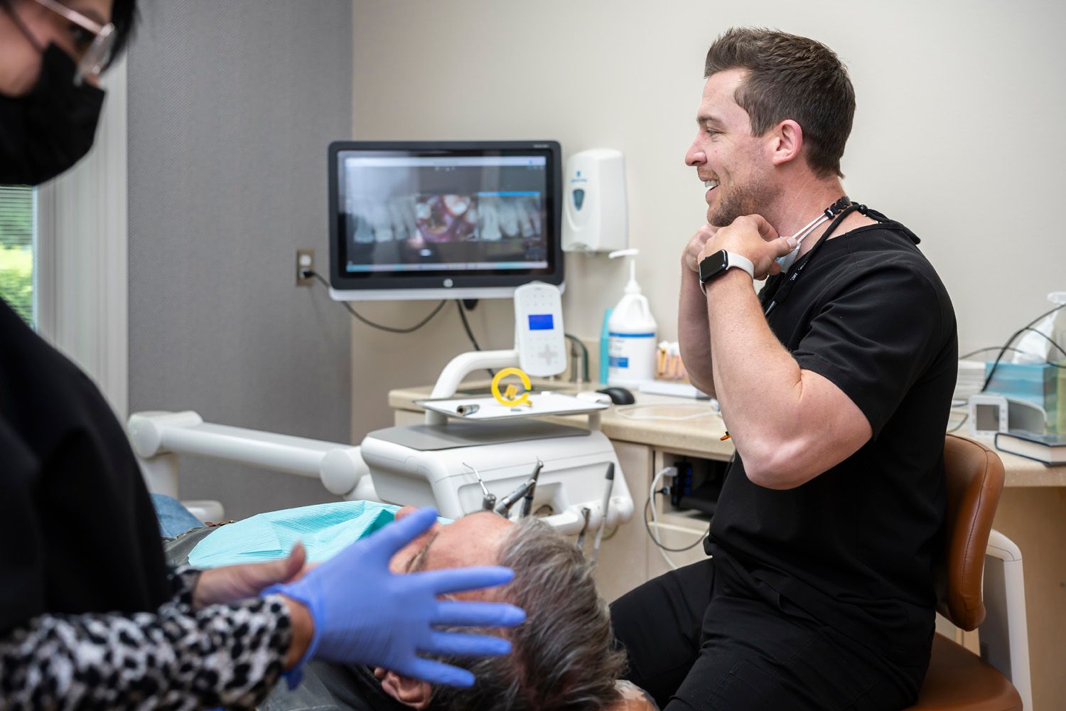 Dr. Crawford is examining a patient 's teeth in a dental office at Maley Family Dental