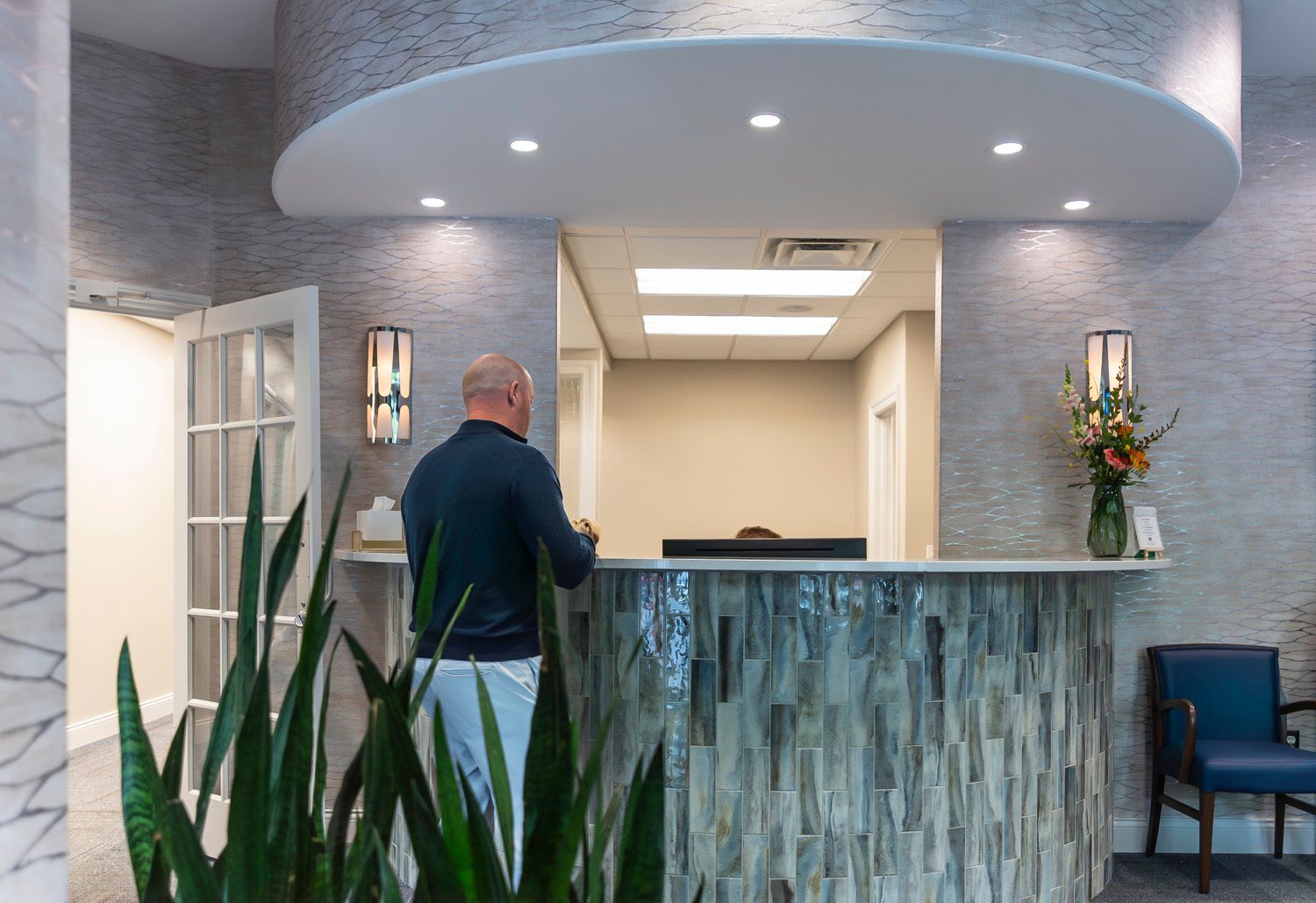 A man is standing at a reception desk in a dental office at Maley Family Dental