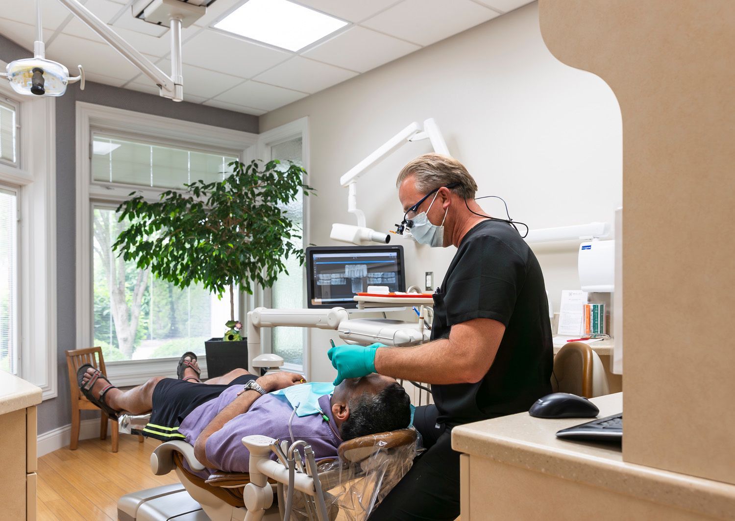 Dr. Maley is examining a patient 's teeth at Maley Family Dental