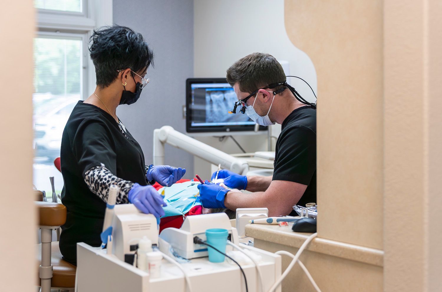 Dr. Crawford and a dental hygienist are working on a patient in a dental office at Maley Family Dental