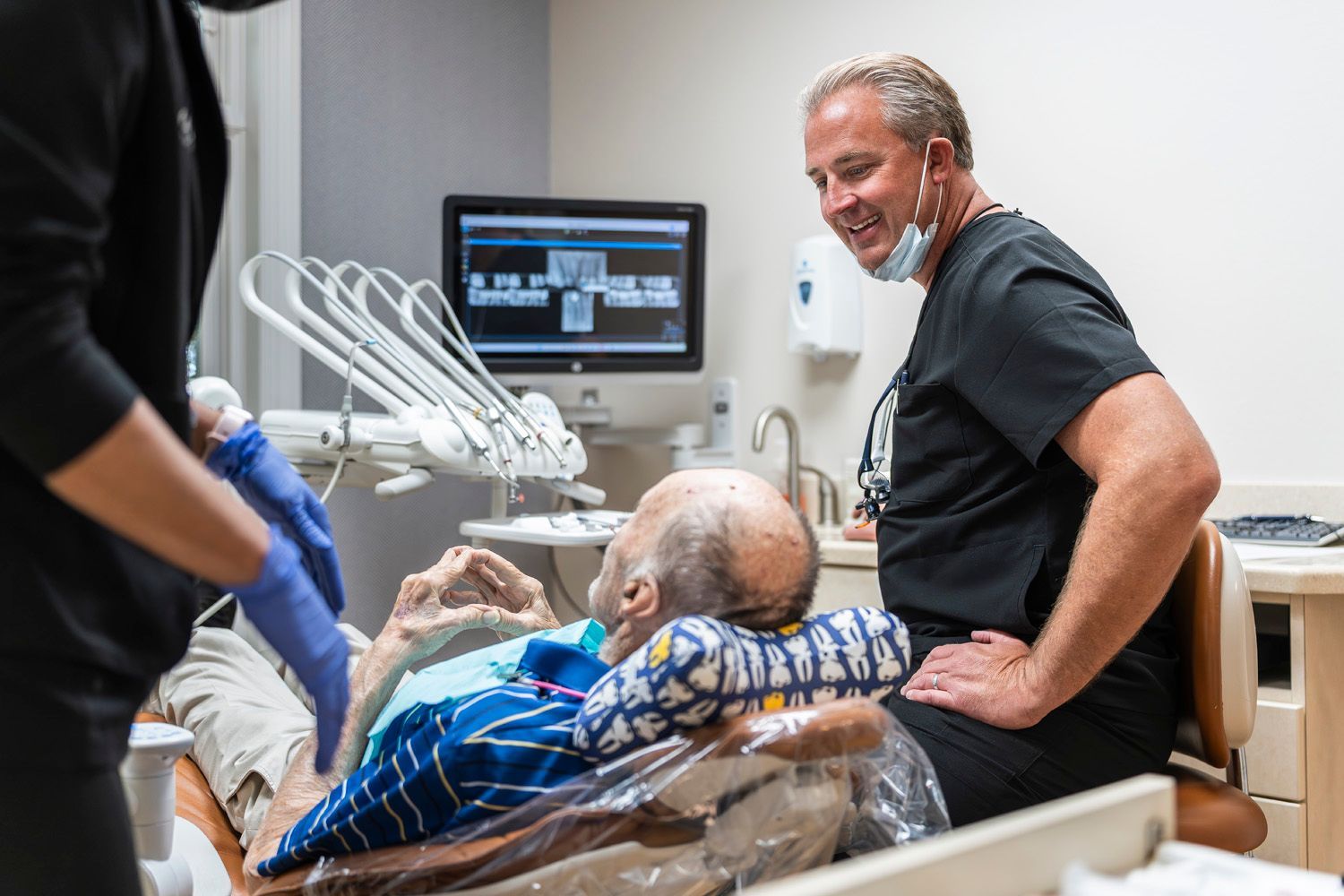 Dr. Maley is talking to a patient in a dental chair at Maley Family Dental