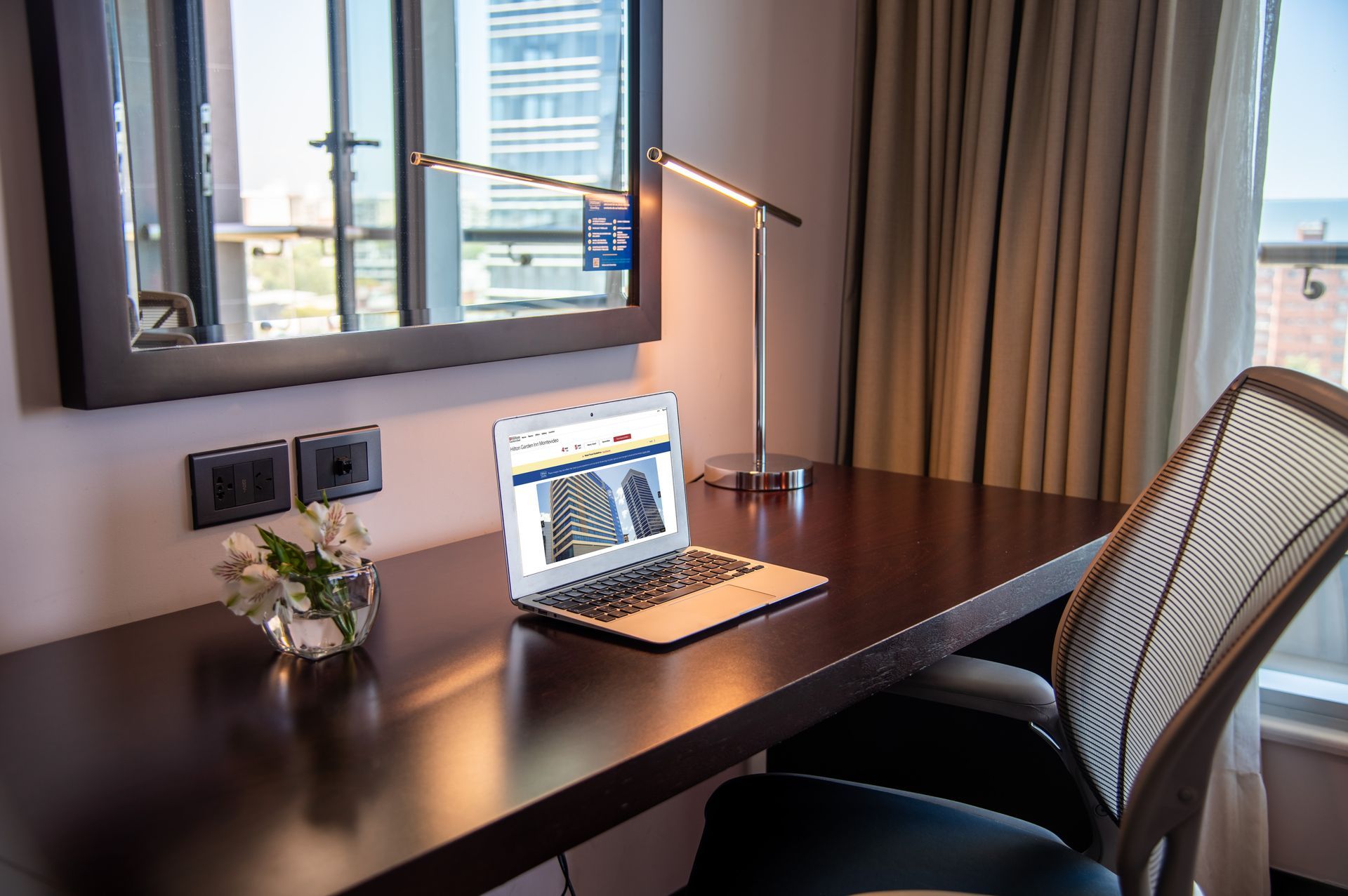 Hay una computadora portátil sobre un escritorio en una habitación de hotel.