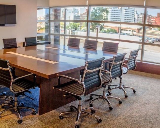 Una sala de conferencias con una mesa larga y sillas.