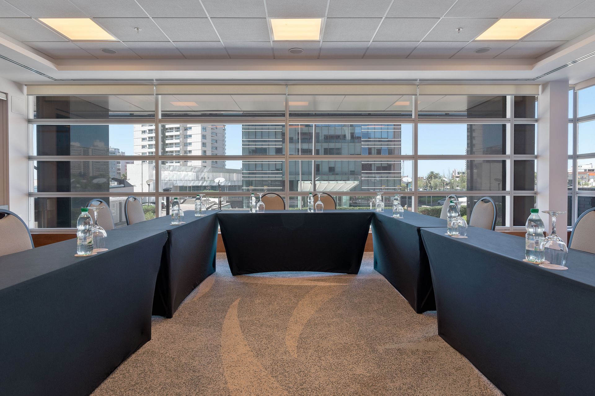 Una sala de conferencias con mesas y sillas largas y un gran ventanal.