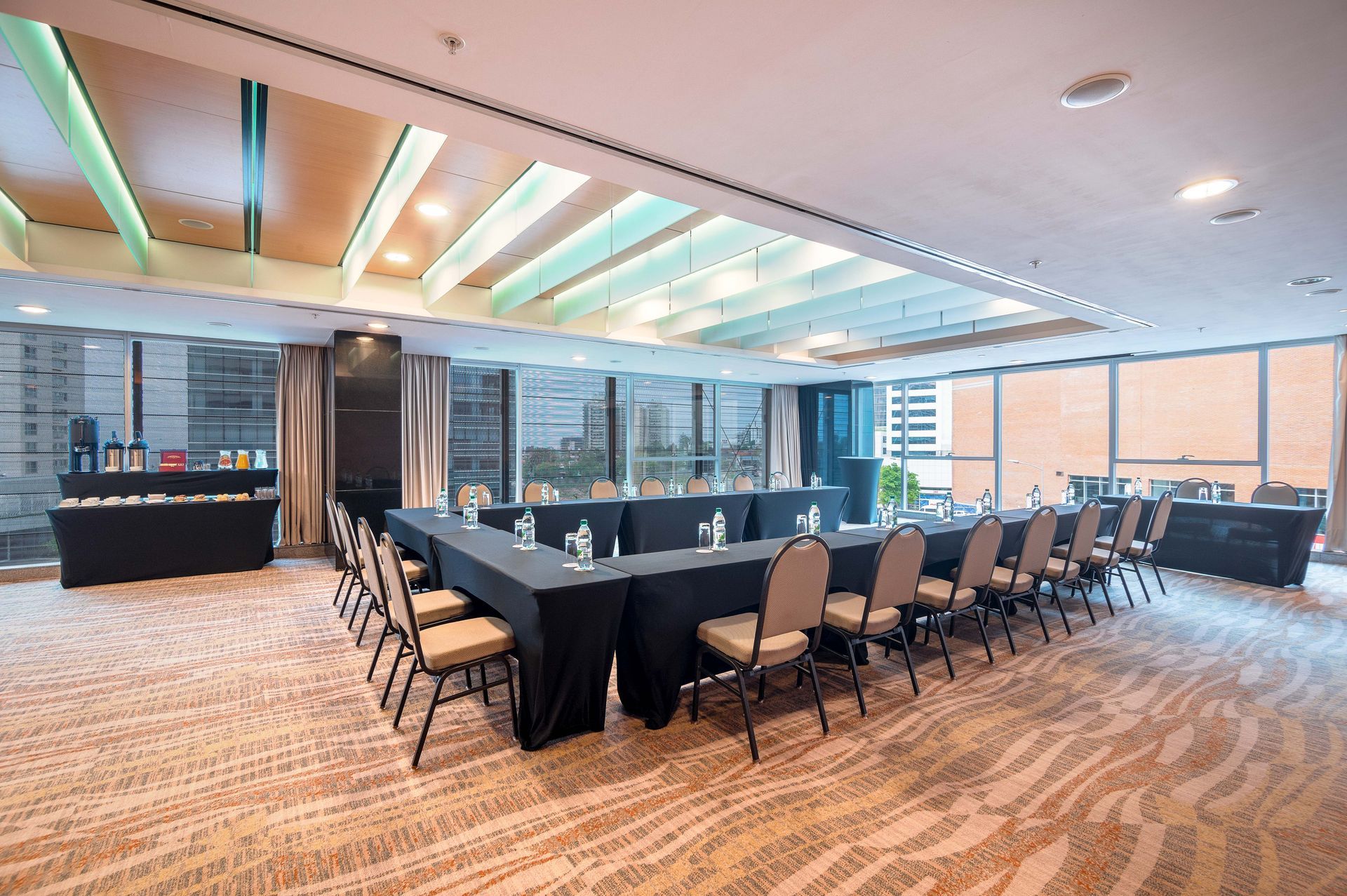 Una gran sala de conferencias con mesas y sillas preparadas para una reunión.