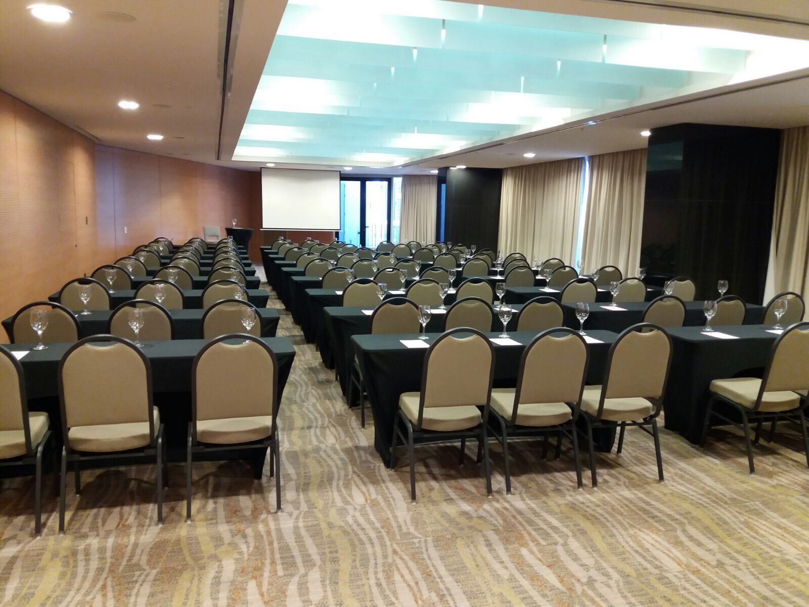 Una gran sala de conferencias con mesas y sillas preparadas para una reunión.