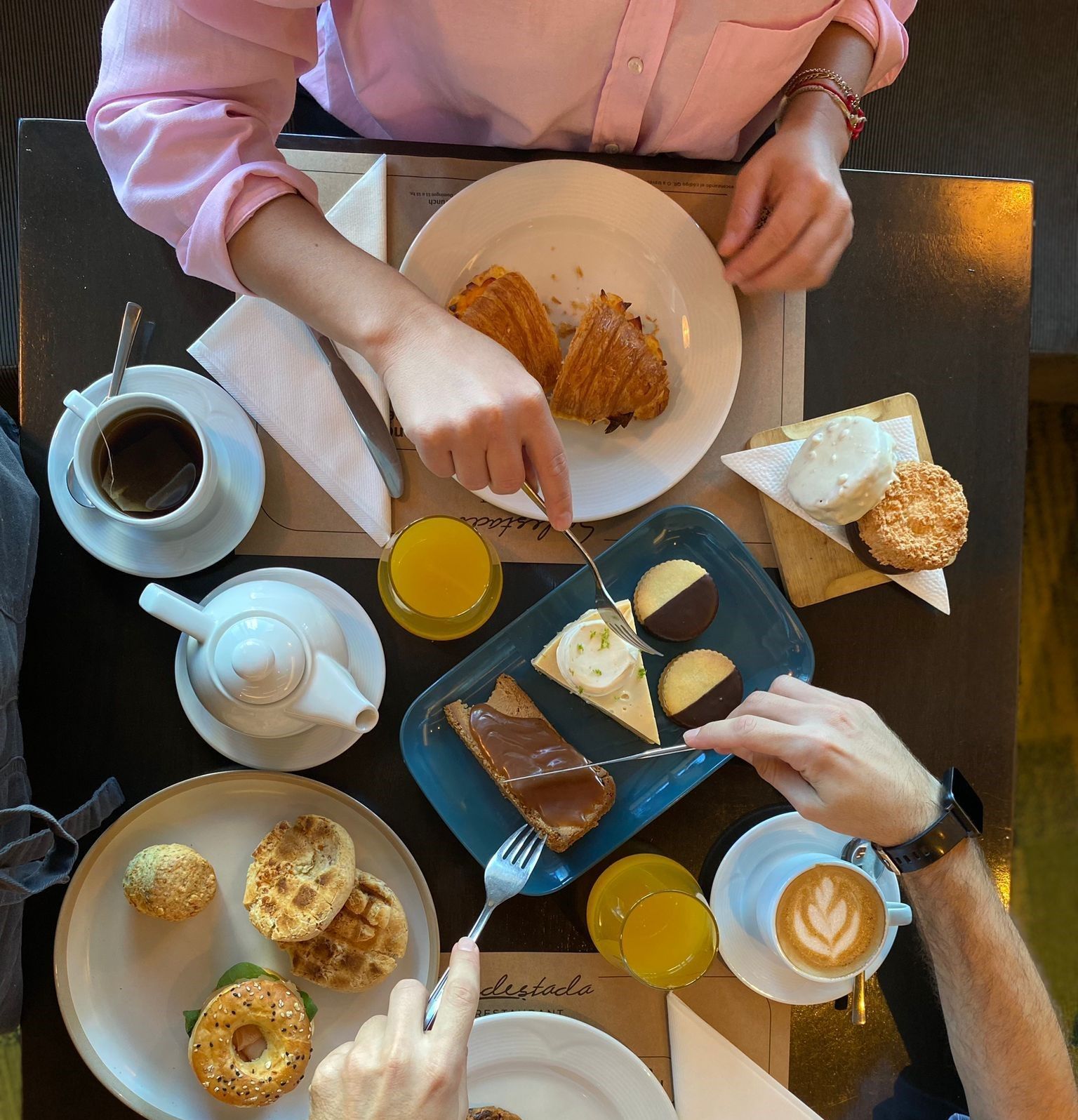 Dos personas están sentadas en una mesa con platos de comida y una taza de café.