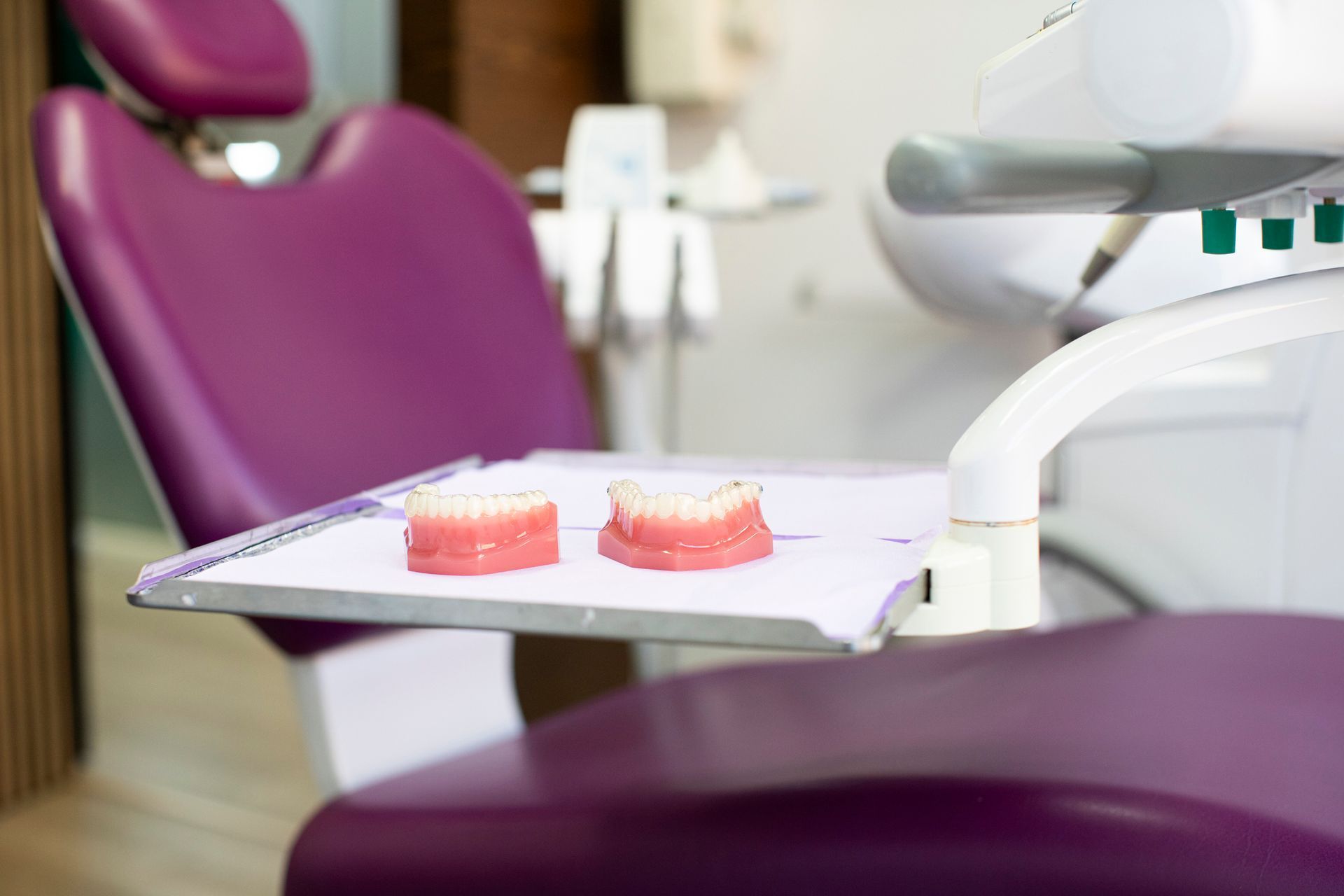 Dentist chair with dentures on a tray. Purple chair, white tray and equipment, dental setting.