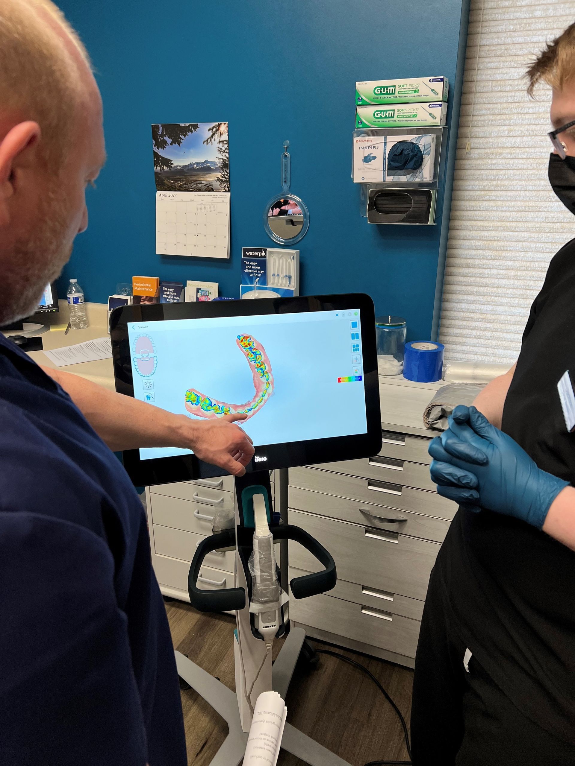 Two people viewing teeth scan on monitor in dental office.