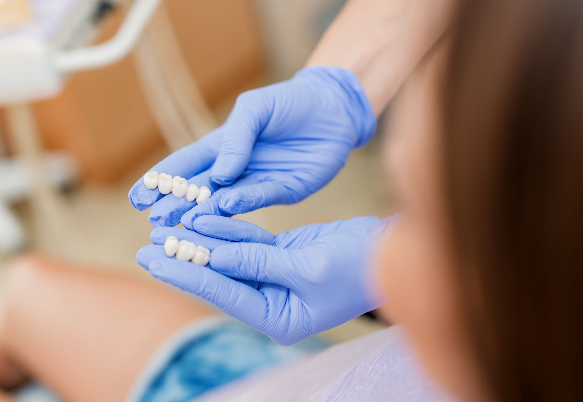A close-up of a dentist’s hands showing porcelain crowns to the patient.