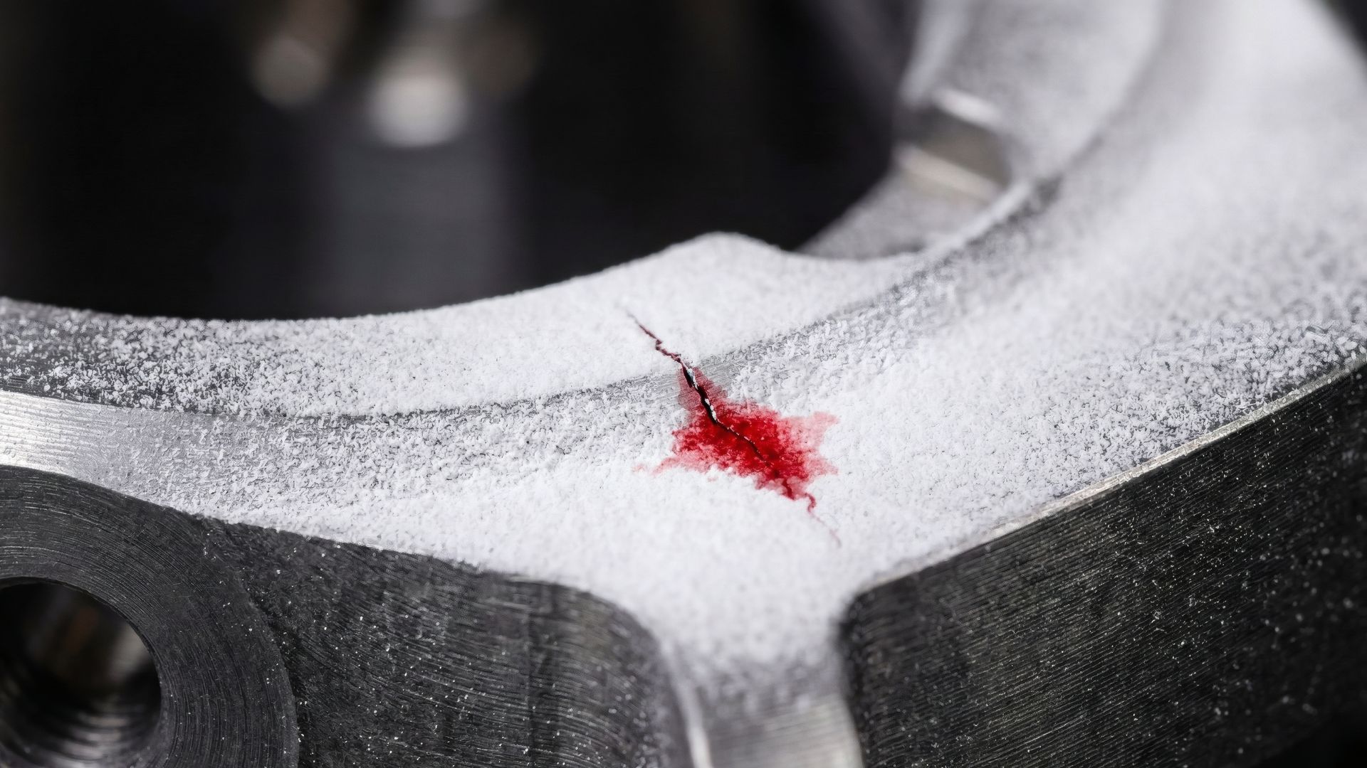 Close-up of a gray metal surface with a small red scratch or paint mark near the edge