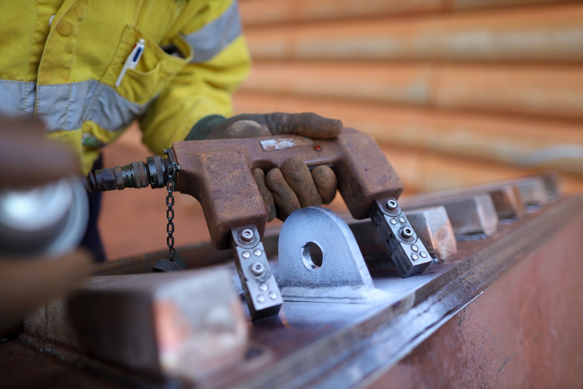 Worker using a magnetic particle testing device to inspect a metal component, applying a spray.