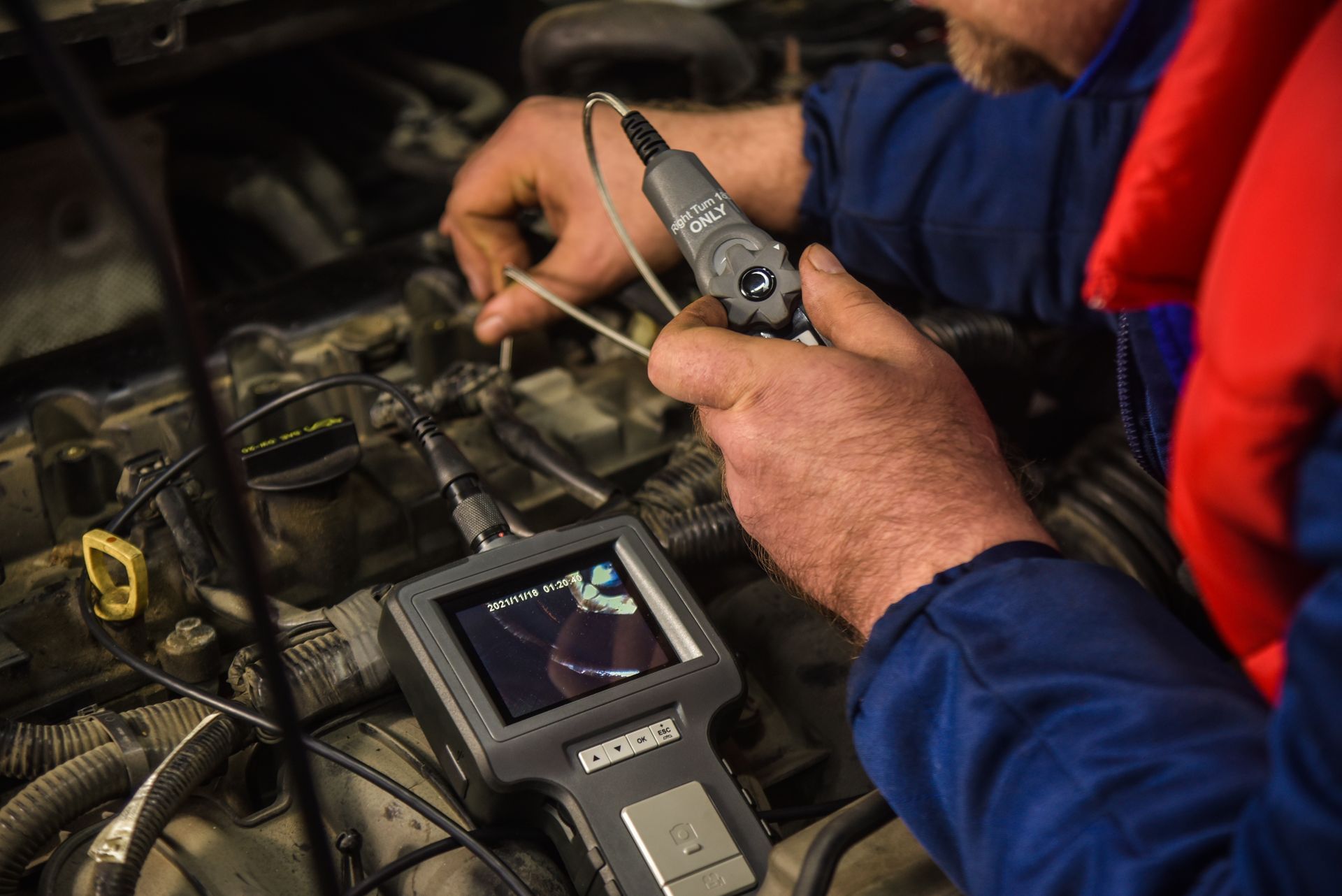 Mechanic using a diagnostic tool to inspect a car engine in a workshop