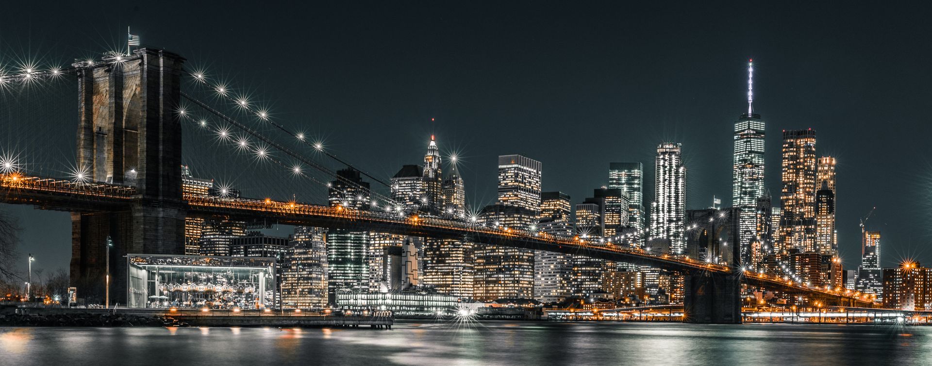 Nighttime city skyline with illuminated bridge and skyscrapers reflected on water