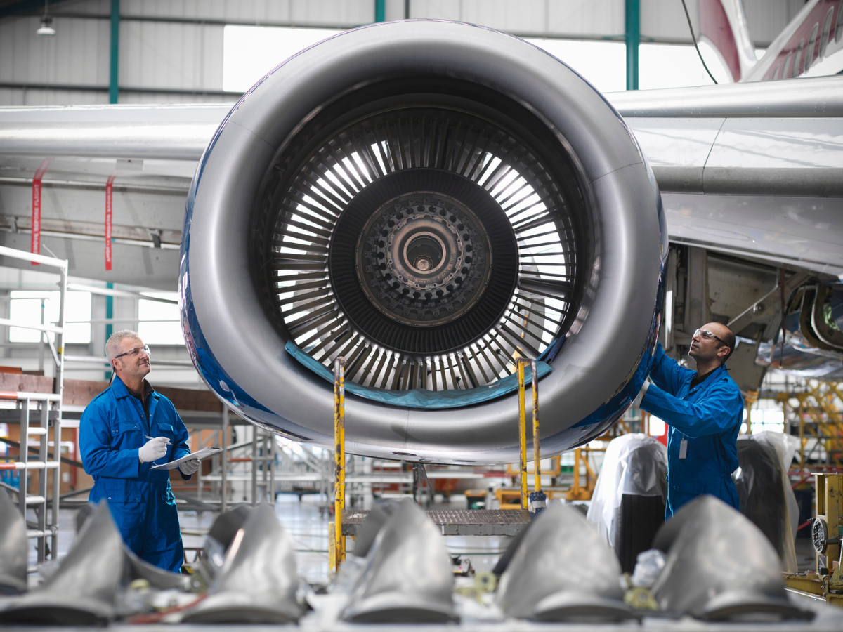 Two men are working on an airplane engine in a factory Two men are working on an airplane engine in a factory