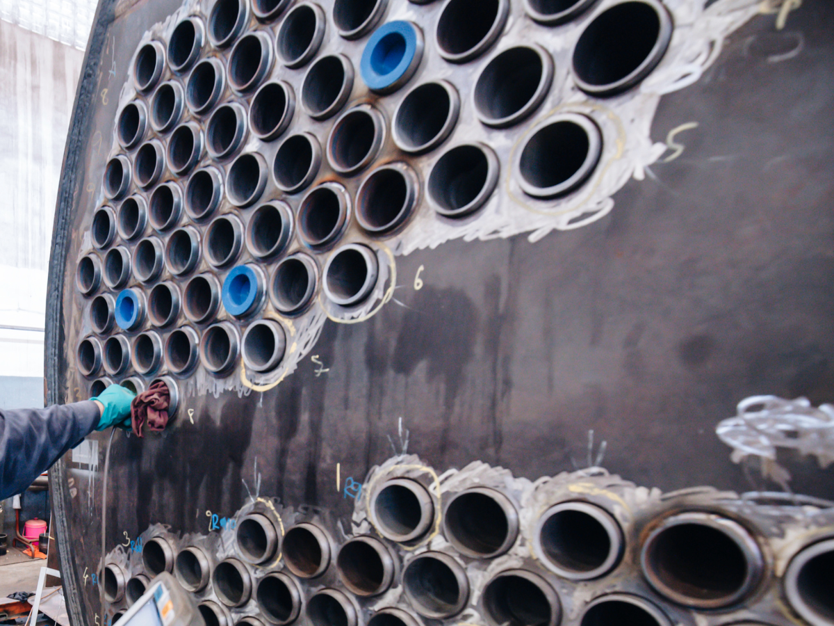 A person is working on a large pipe with holes in it A person is working on a large pipe with holes in it