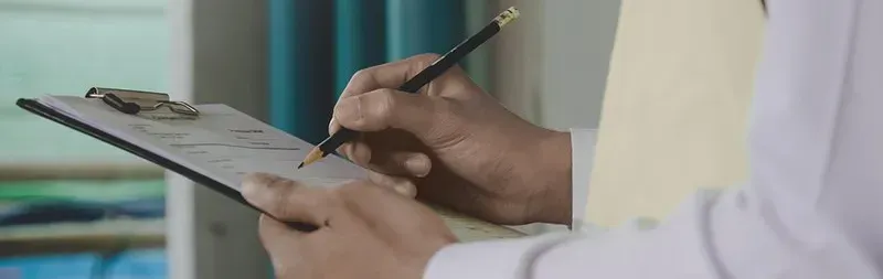 A person is writing on a clipboard with a pencil. A person is writing on a clipboard with a pencil.
