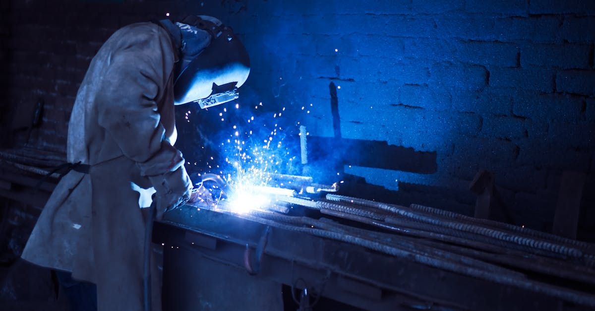 A man is welding a piece of metal in a dark room.