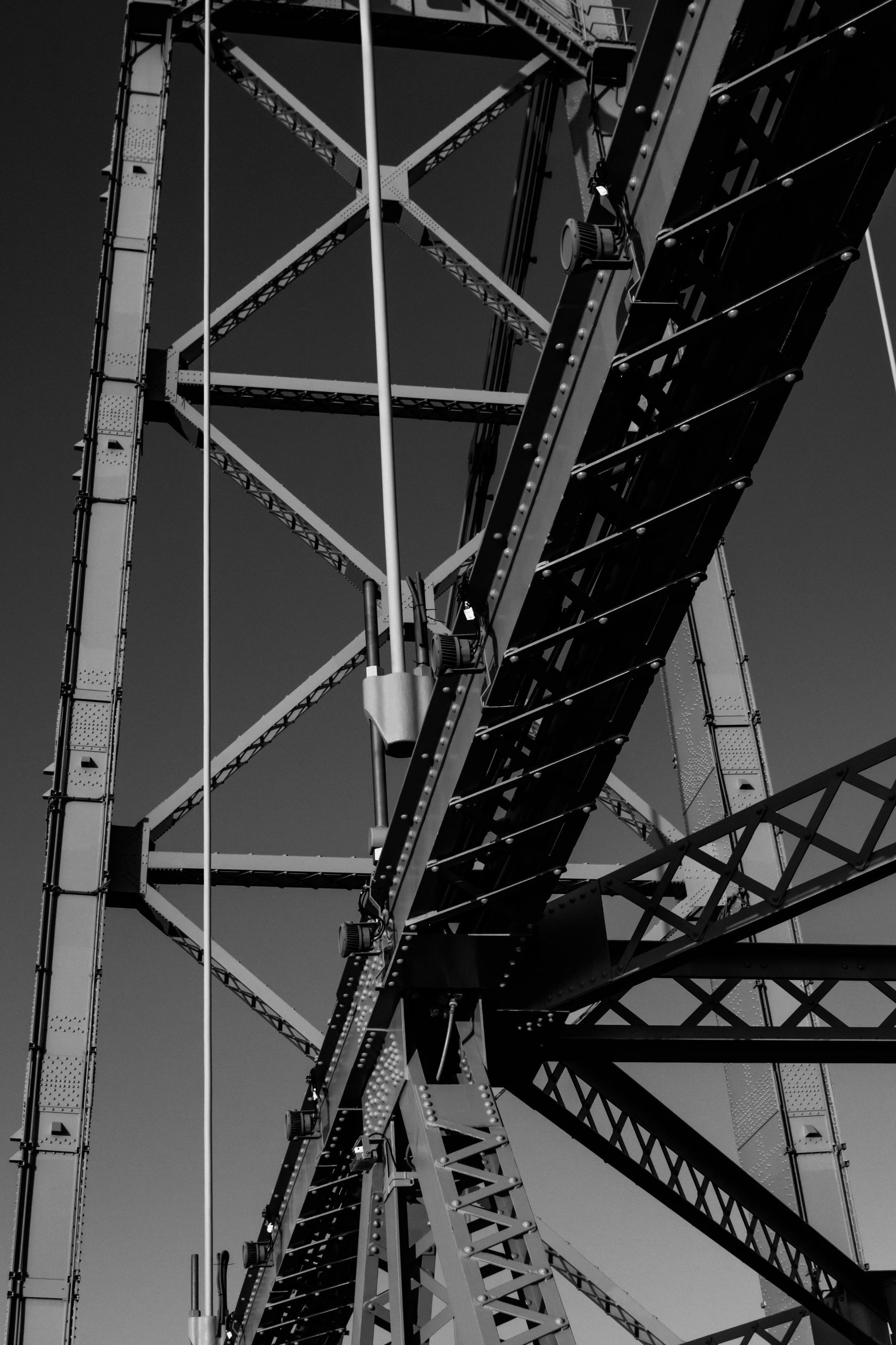A black and white photo of a bridge with a blue sky in the background