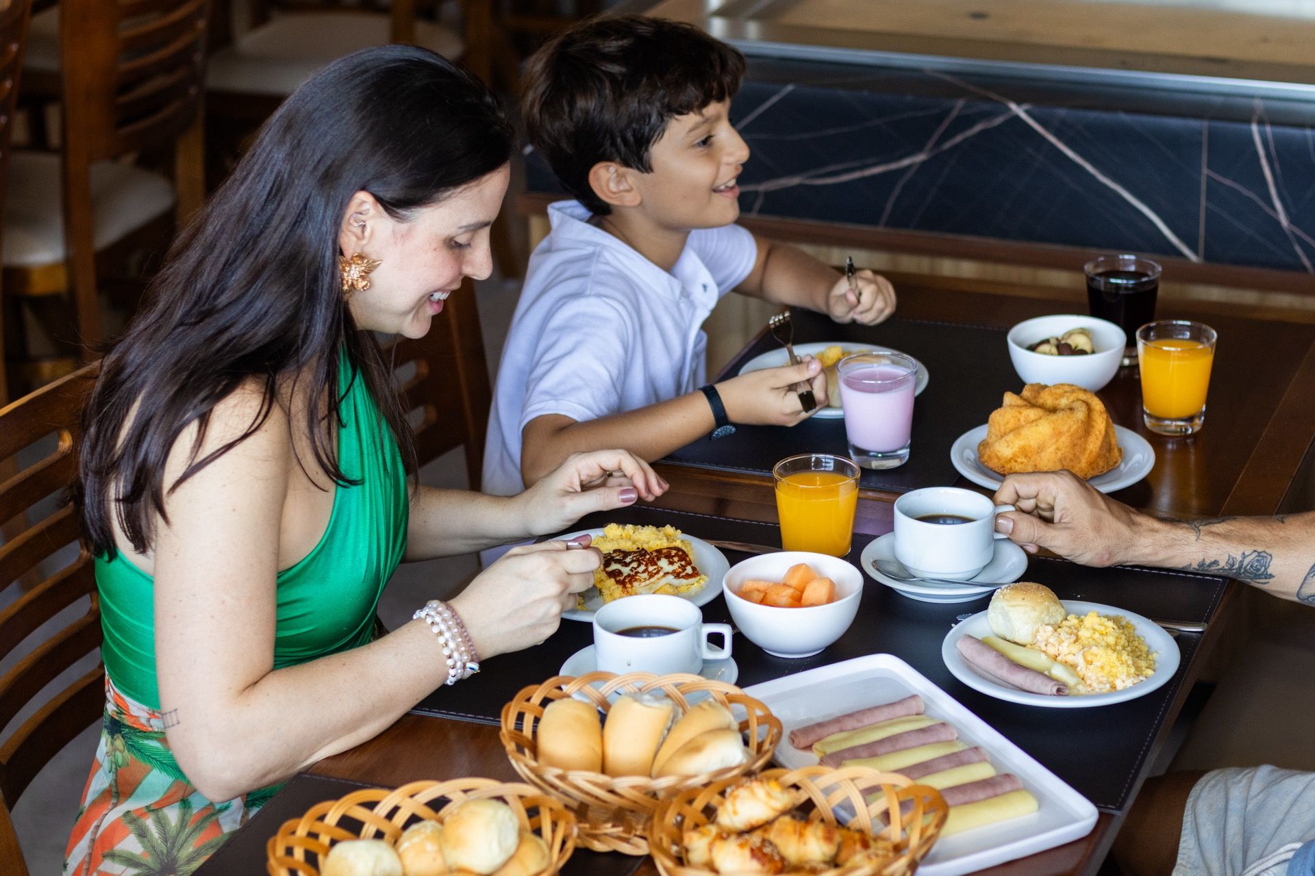Uma família está sentada à mesa tomando café da manhã.