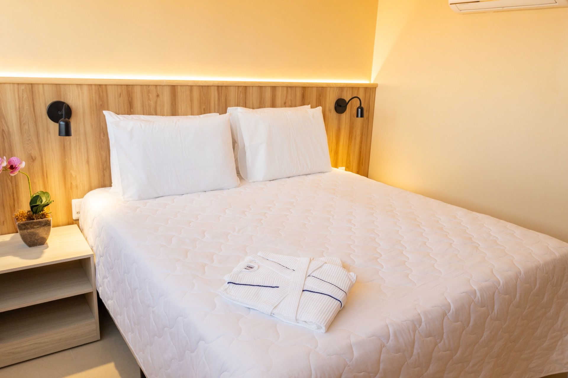 Um quarto de hotel com uma cama king size e uma cabeceira de madeira.