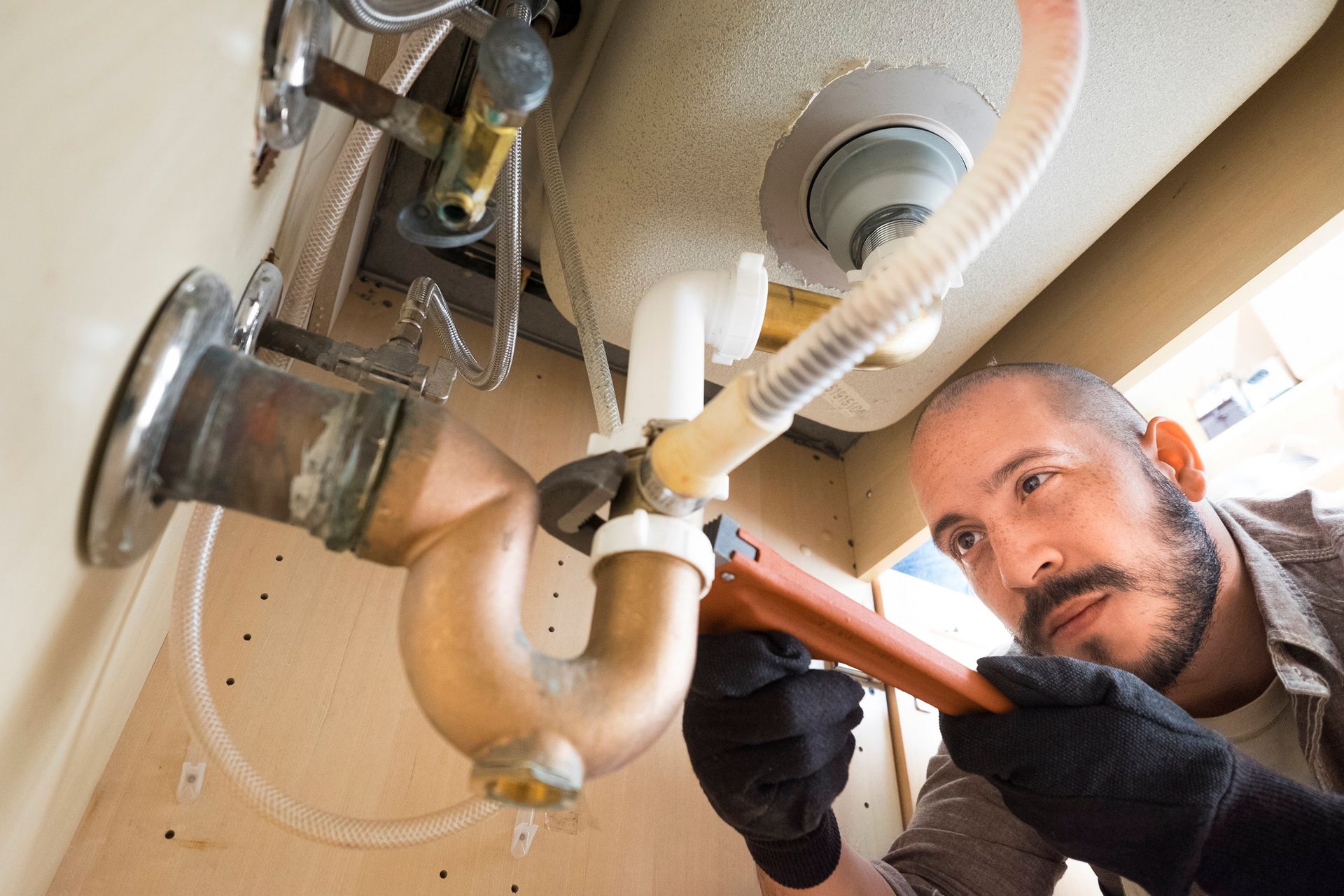 A Man is Fixing a Sink Pipe with a Wrench | San Bernardino, CA | Full Spectrum Plumbing Inc.