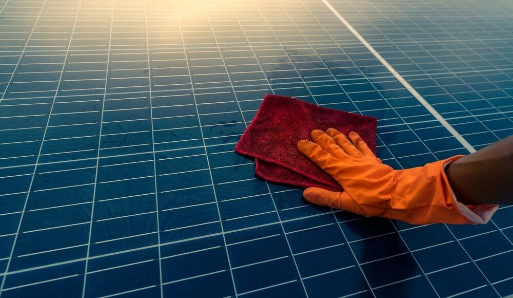Person Wearing Orange Gloves is Cleaning a Solar Panel With a Cloth — Abstract Window Cleaning in Tweed Heads, NSW