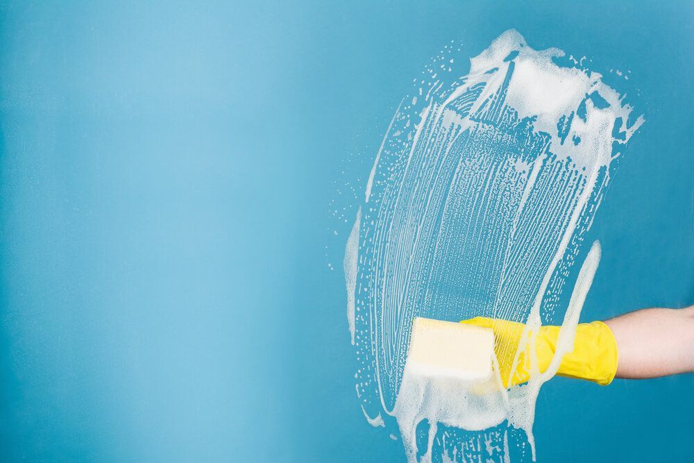 Person Wearing Yellow Gloves is Cleaning a Window With a Sponge — Abstract Window Cleaning in Hopkins Creek, NSW