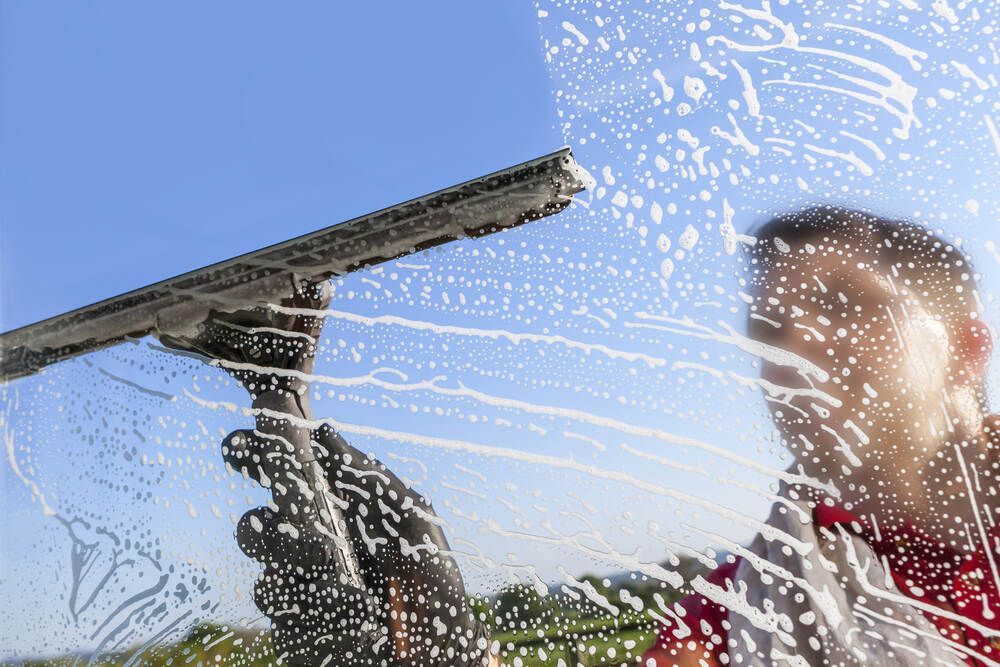 Man is Cleaning a Window With a Squeegee — Abstract Window Cleaning in Hopkins Creek, NSW