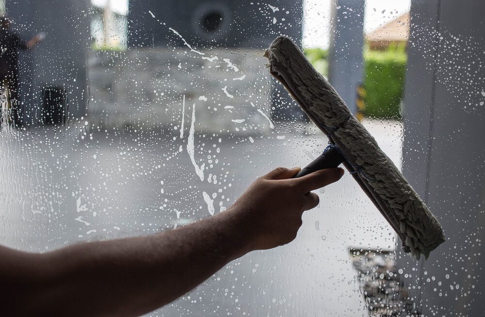 Person is Cleaning a Window With a Squeegee — Abstract Window Cleaning in Pottsville, NSW