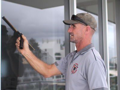 Man is Cleaning a Window With a Squeegee — Abstract Window Cleaning in Hopkins Creek, NSW