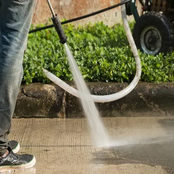 Person is Using a High Pressure Washer to Clean a Sidewalk — Abstract Window Cleaning in Hopkins Creek, NSW