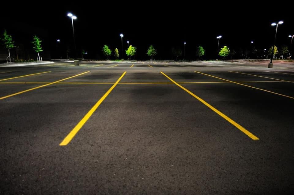 An empty parking lot at night with trees in the background