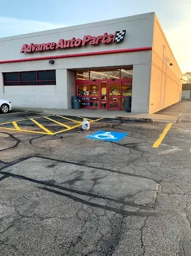 A handicapped parking spot is painted in front of an advance auto parts store.