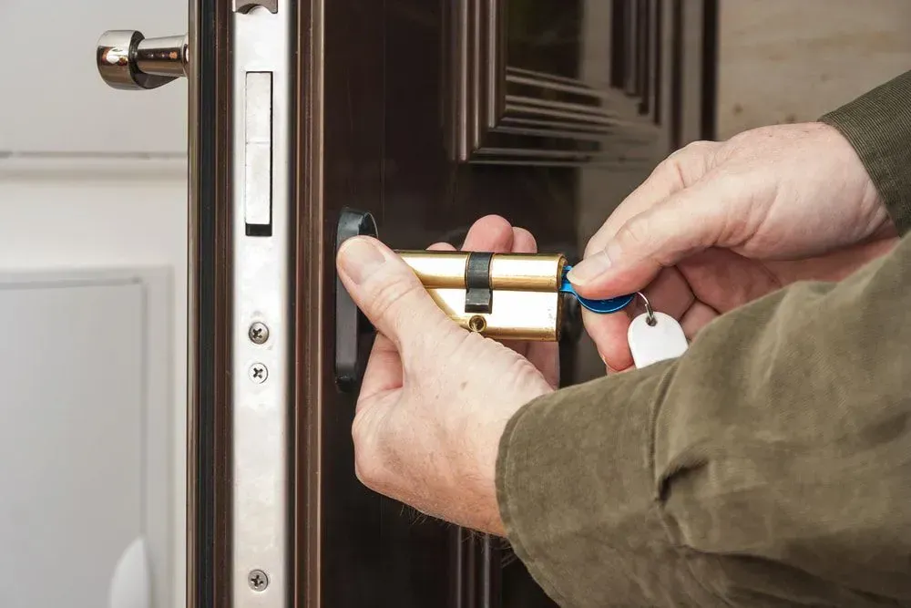 Person Installing a New Lock Cylinder in a Dark Brown Door, Silver Hardware — Shaine Hunter Locksmiths in Camooweal, QLD