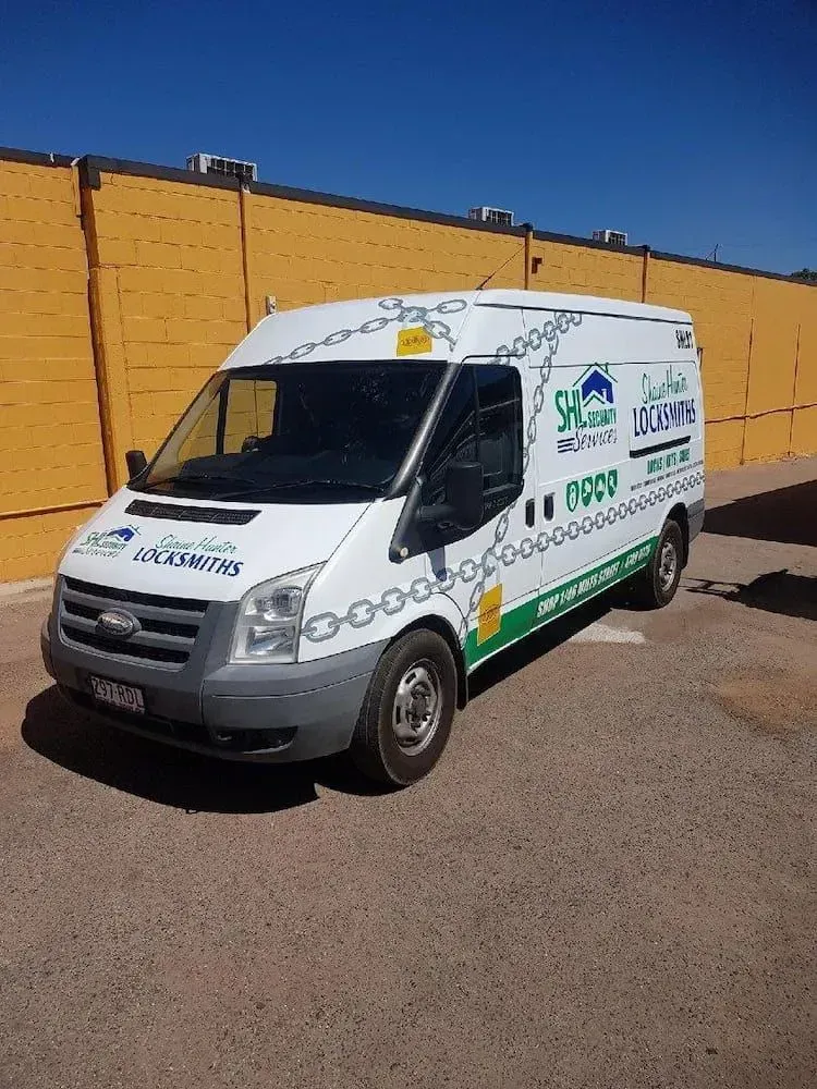 White Locksmith Van Parked Against a Yellow Wall — Shaine Hunter Locksmiths in Mount Isa City, QLD