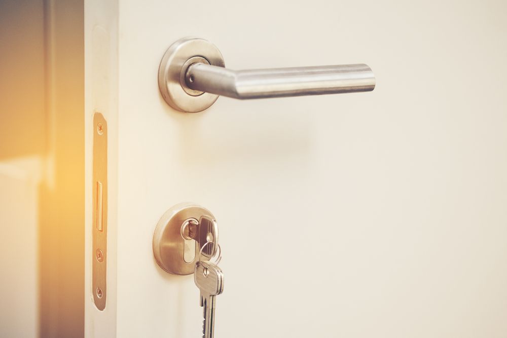 White Door With Silver Handle and Key in the Lock — Shaine Hunter Locksmiths in Camooweal, QLD